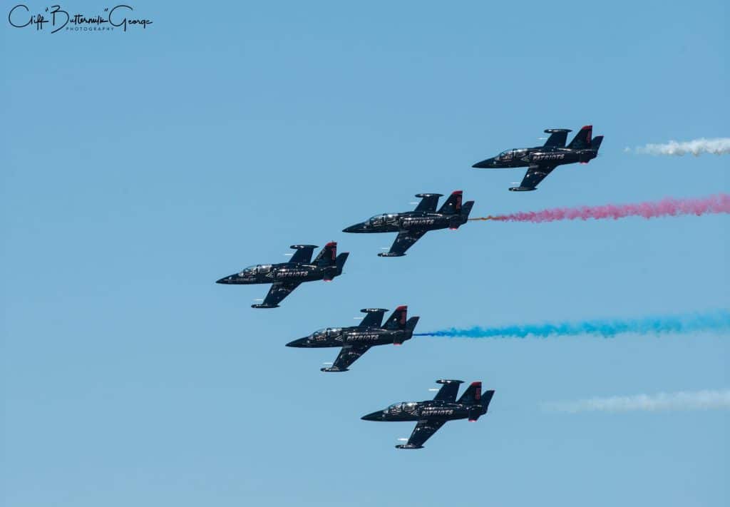 Formation for Patriots fighter jet team with red, white and blue smoke trails